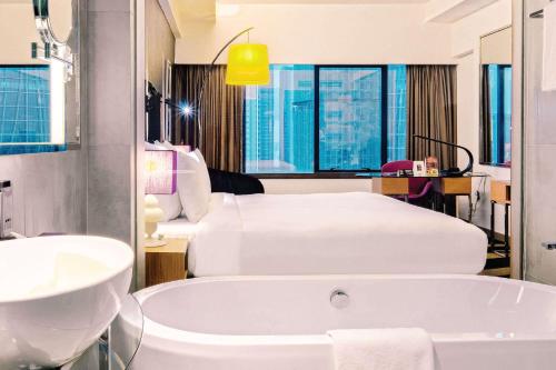 Wyndham Grand Bangsar Kuala Lumpur في كوالالمبور: حمام بسريرين وحوض استحمام