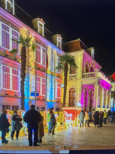 a group of people walking in front of a building with christmas lights at MEA Centre Apartment in Shkodër