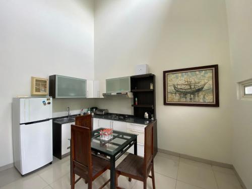 a kitchen with a table and a white refrigerator at The 8 House – Surabaya City Center in Surabaya