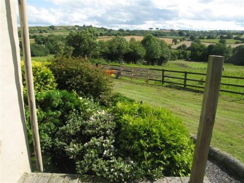 uma vista para um campo com uma cerca e flores em Derbyshire Holiday Cottages em Holmesfield