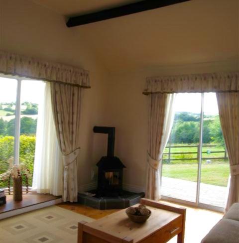 a living room with a wood stove and windows at Derbyshire Holiday Cottages in Holmesfield