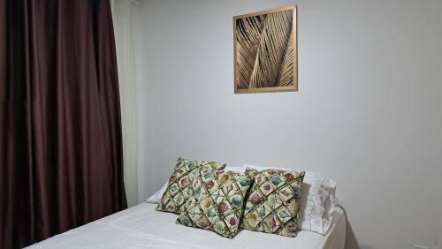 un letto con cuscino e una foto appesa al muro di Maraca Beach Residence 1 apartamento 401 a Porto De Galinhas