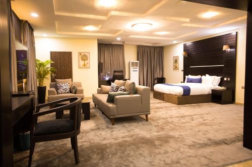 a hotel room with a bed and a couch and chairs at ED&DRE Luxuria Hotel in Ibadan