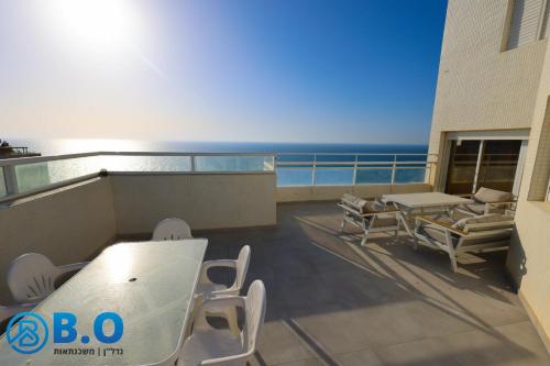 a balcony with a table and chairs and the ocean at על הים in Netanya