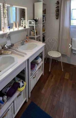 a bathroom with two sinks and a mirror and a chair at maison tout confort in Saint-Vivien-de-Médoc