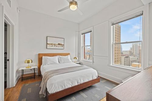 a white bedroom with a bed and two windows at The Maverick, powered by Placemakr - River Walk in San Antonio