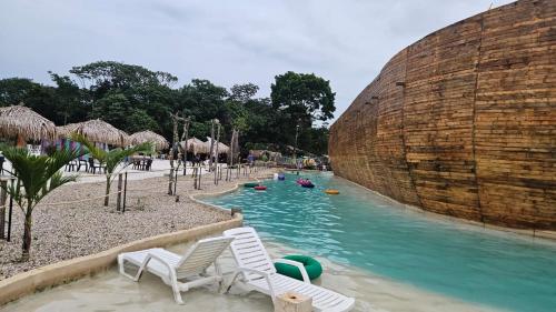 Tauramena的住宿－Cabaña campestre arca de Noé，一个带椅子的游泳池,在水上公园里有人