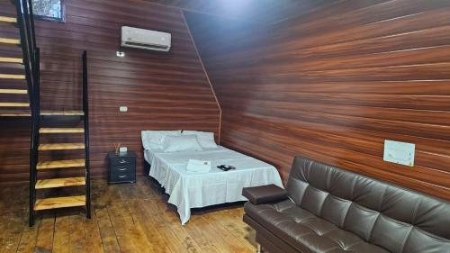 Pokój z łóżkiem i kanapą oraz drewnianymi ścianami w obiekcie Cabaña campestre arca de Noé w mieście Tauramena