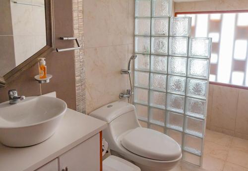 y baño con lavabo, aseo y espejo. en TEYFA Hospedaje - Casa, en Atuntaqui