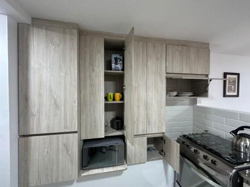 a kitchen with wooden cabinets and a stove at loft central, cerca a laureles GUARDA MELETAS GRATIS!! in Medellín