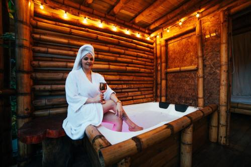 a woman sitting in a bath tub with a glass of wine at Cabaña Manantial del Turpial in Jardin