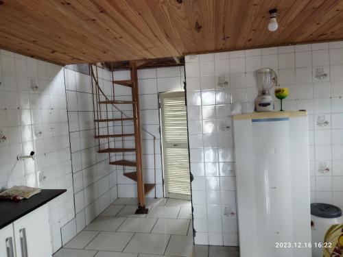 eine Küche mit einer Wendeltreppe und einem Kühlschrank in der Unterkunft Cabana da barra in Içara