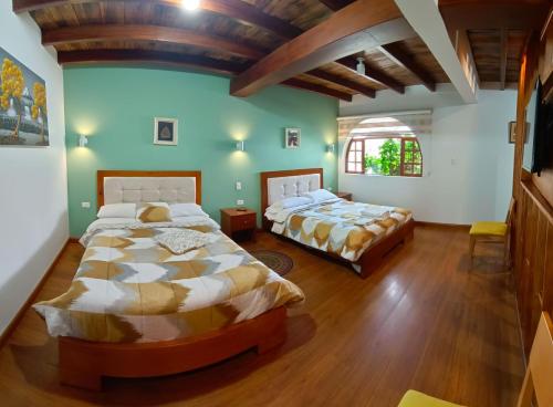 Duas camas num quarto com paredes verdes e pisos em madeira em TEYFA Hospedaje - Casa em Atuntaqui