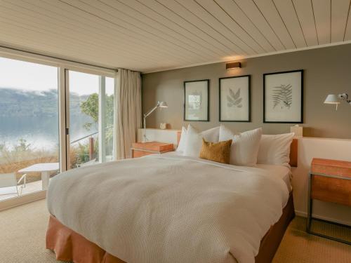 a bedroom with a large bed and a large window at Rosewood Matakauri in Queenstown