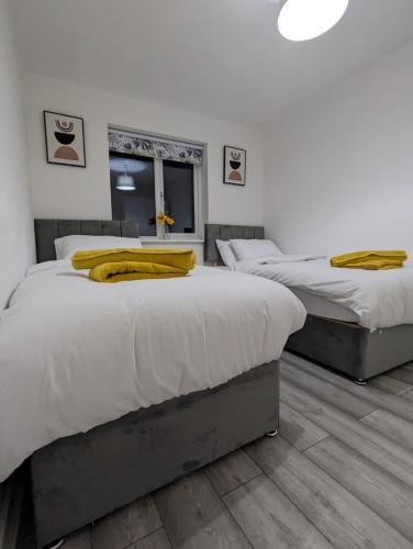 um quarto com 3 camas com almofadas amarelas em Freshen-up stays Doncaster em Bentley