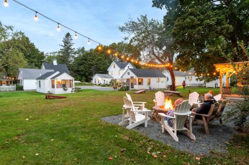 a group of people sitting around a fire in a yard at Bar Harbor Cottages & Suites in Bar Harbor
