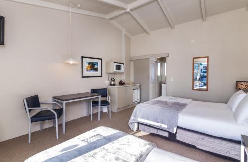 a bedroom with a bed and a desk and a table at Twin Peaks Lakeside Inn in Taupo