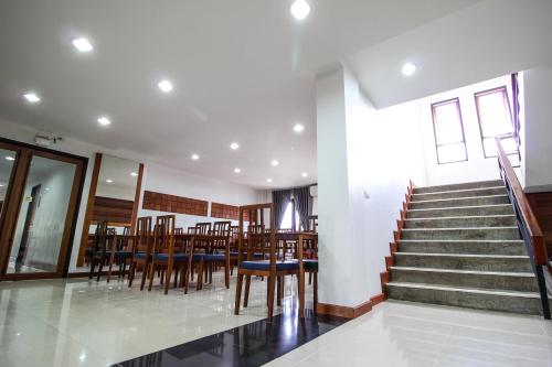 a dining room with a table and chairs and stairs at Tai-Shan Suites in Ratchaburi