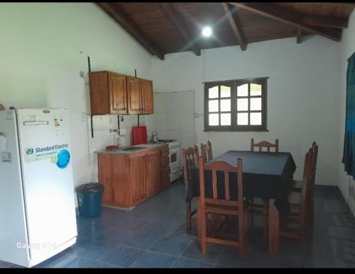 a kitchen with a table and chairs and a refrigerator at Cabaña Iberá in Colonia Carlos Pellegrini