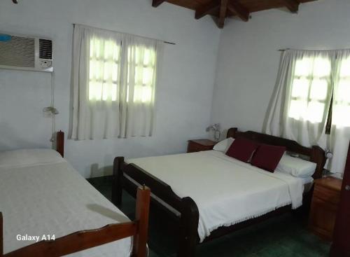 a bedroom with two beds and two windows at Cabaña Iberá in Colonia Carlos Pellegrini