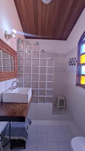 La salle de bains blanche est pourvue d'un lavabo et d'une fenêtre. dans l'établissement Casa da felicidade praia do forte 2 quartos, à Itaparica Town