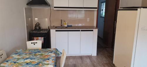 a kitchen with white cabinets and a table and a stove at La Isla - Araminda in Araminda