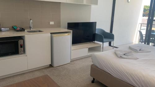 a room with a kitchen and a bed and a sink at Self Check in Modern Studio Apartment in Mackay