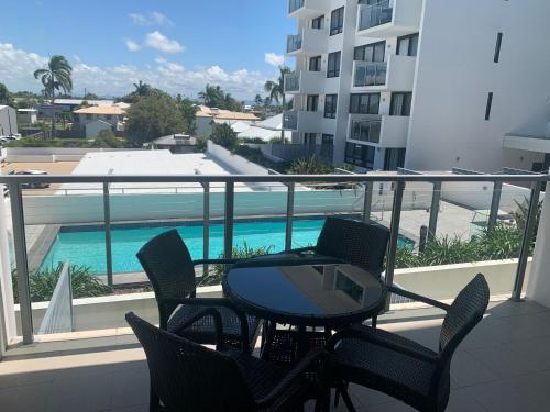 a balcony with a table and chairs and a swimming pool at Self Check in Modern Studio Apartment in Mackay