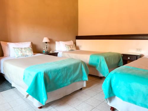 a hotel room with two beds with blue and green sheets at Casa del Sol Cafayate in Cafayate
