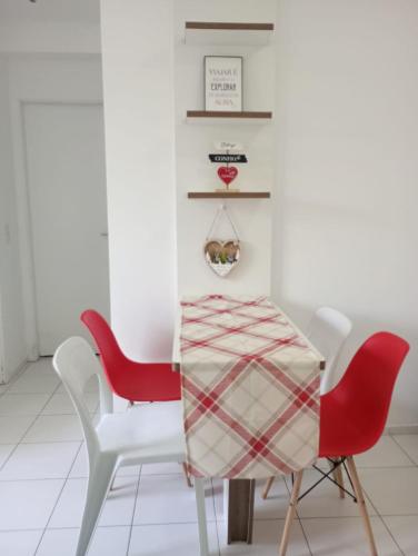 a dining room with two red chairs and a table at Apartamento 1 km da praia do aracagir confortavel in São-José-do-Ribamar