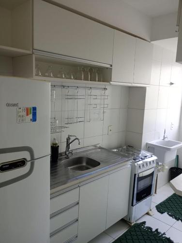 a white kitchen with a sink and a stove at Apartamento 1 km da praia do aracagir confortavel in São-José-do-Ribamar