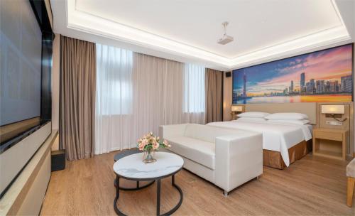 a hotel room with a white bed and a tv at Vienna Hotel Shenzhen Longshen Subway Station in Tiantangwei