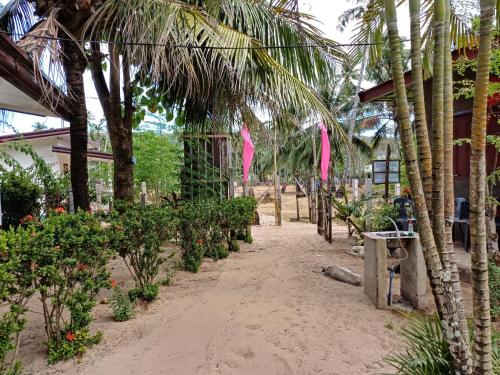 a beach with palm trees and a building at Calitang Pearl Cottage in Nacpan