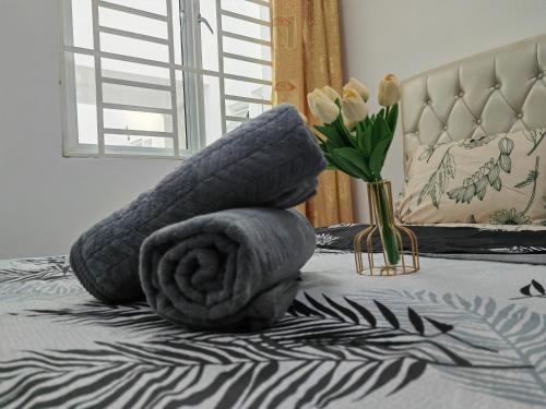 a towel on a bed with a vase of flowers at Homestay Pangsapuri Simfoni 3BR 7Pax Kuah Langkawi in Kuah