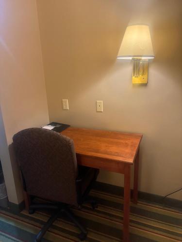 a desk with a chair and a lamp on a wall at Super 8 by Wyndham Sparta in Sparta
