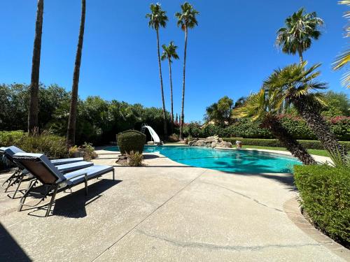 a bench next to a swimming pool with palm trees at Paradise in Scottsdale with Pool Oasis & Game Room in Phoenix