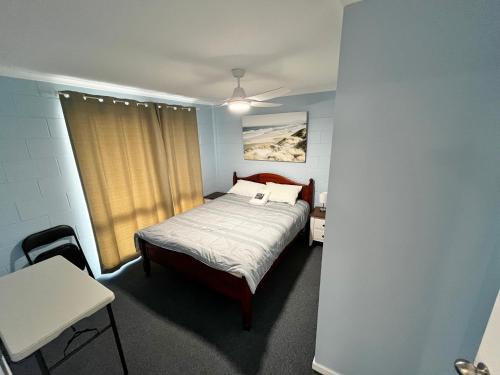 1 dormitorio con cama, mesa y escritorio en Hibiscus by the Beach, en North Coast