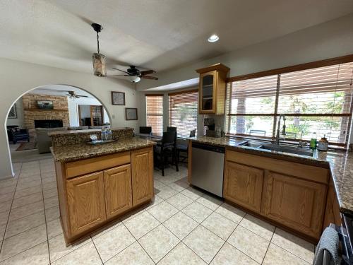 a large kitchen with wooden cabinets and a living room at Paradise in Scottsdale with Pool Oasis & Game Room in Phoenix