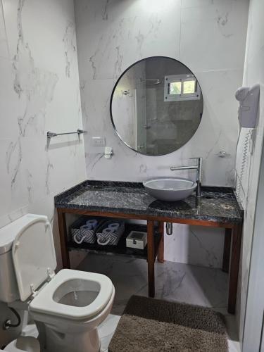 Un baño con lavabo, inodoro y espejo. en Raíces serranas, en Villa Las Rosas