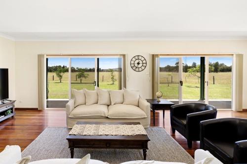 a living room with a couch and chairs and windows at Black Creek Paddock in Lovedale