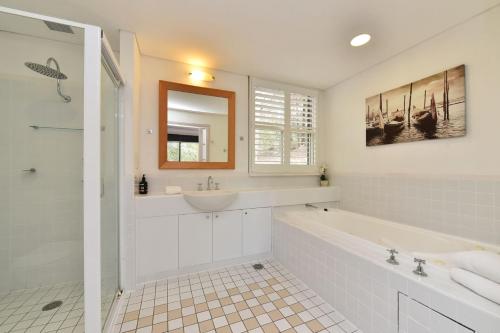 Baño blanco con bañera y lavamanos en Villa Spa Executive 1br Burgundy located within Cypress Lakes Resort en Pokolbin