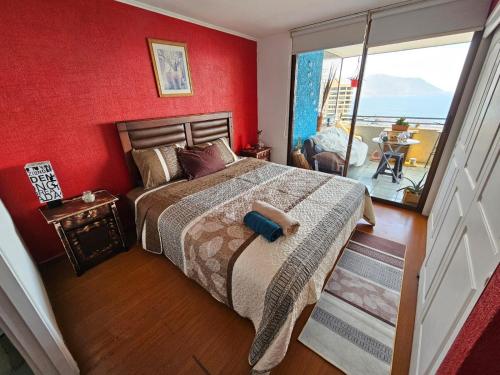 um quarto com uma cama com uma parede vermelha em Habitación duerme y disfruta junto al mar em Iquique