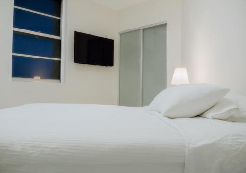1 cama blanca con almohadas blancas y TV en la pared en Live Amazingly by the Beach - 00388, en Miami Beach