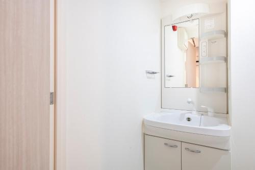 Baño blanco con lavabo y espejo en Brilliant MK- III, en Tokio