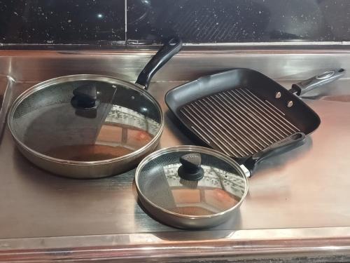 two pans sitting on top of a stove at Entre Aves hospedaje in Luna Park
