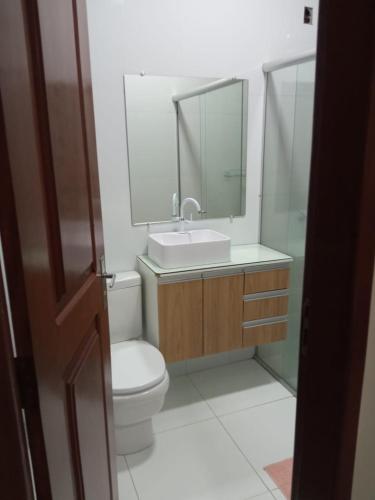 a bathroom with a toilet and a sink and a mirror at House Suites in Paragominas