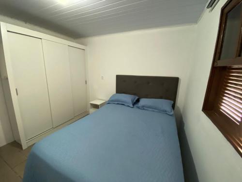 1 dormitorio con 1 cama con 2 almohadas azules en BS01- Casa Aconchegante| Equipada| Churrasqueira|, en Balneário Barra do Sul