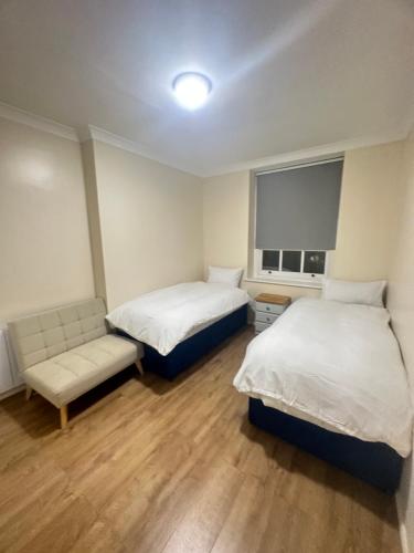 倫敦的住宿－Lovely 3 bed regent park，客房设有两张床、一张沙发和一个窗口。