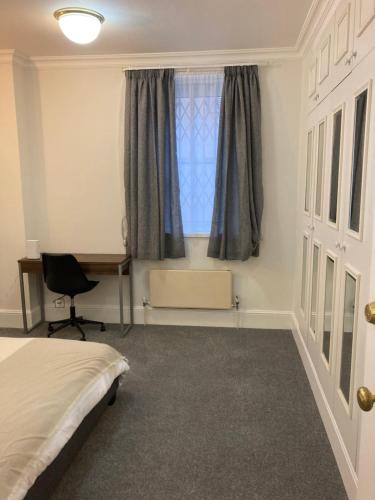 a bedroom with a bed and a desk and a window at Oxford Street Two Bed Apartment in London