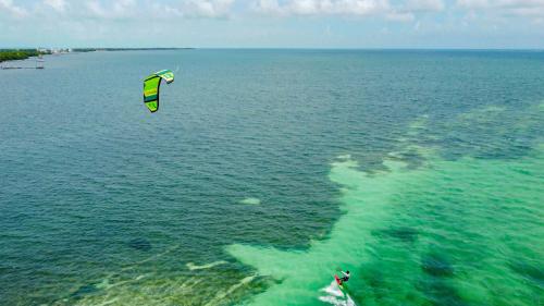 a person is flying a kite over the water at Hidden Treasure Vacation Home BayBlue Suite 1 in Belize City